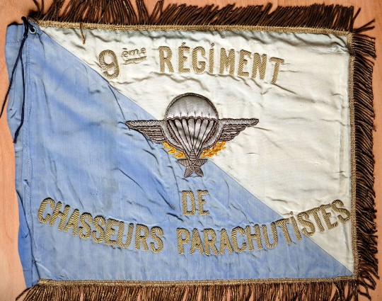 Ce Fanion est tranché sur les deux faces .BLEU roi à la hampe Bleu clair ou peut être BLANC ( couleur de substitution ) pour les parties flottantes .A l' avers finement brodé en cannetille  un Brevet de Parachutiste et l'inscription 9° Régiment de Chasseurs Parachutistes