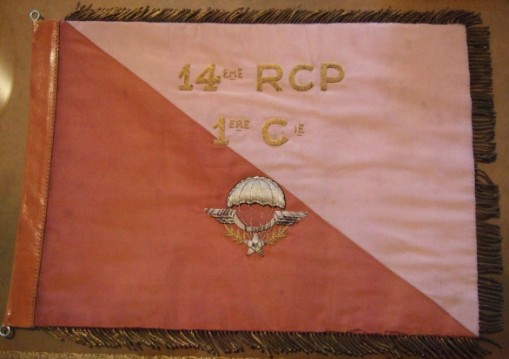 a l' avers il porte en broderies de cannetilles d' or l' identification de l'unité  14eme RCP 1ere Cie  , ainsi qu'un Brevet de Parachutiste aux contours approximatifs  .Au revers il porte la reproduction de l'insigne du 14° Ce Fanion est discrétement frangé d'or ,c' est probablement le seul détail qui le distingue du Fanion de première dotation ..