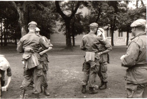 Séance de rasage interactive au camp de GER .Le chef de section ayant constaté que ses hommes n' étaient pas rasés de près au rassemblement avait organisé une séance de rasage mutuel Quart aux pieds pour humidifier le blaireau ,les parachutistes par binones se rasent mutuellement .Notez les imperméables portés au ceinturon sans courroies de capote "  