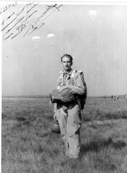  (parachutes en cours de descente en arrière plan )Le parachutiste main sur le ventral porte une combinaison de saut .