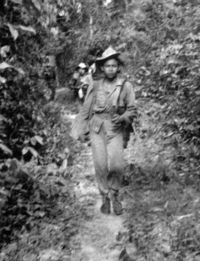 Le long d'un sentier en zone accidentée et boisée .L' éclaireur de tête ,un jeune para Lao ,avec son PM Mat 49 ne parait pas trop stressé .Comme tous ses camarades il porte un chapeau de brousse de couleur claire au modèle 1949.