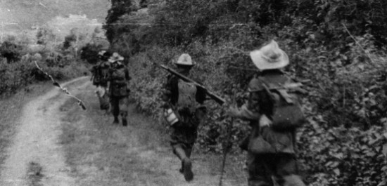 Marchant sur une piste carrossable ces paras LAO vus de dos portent leur arme en bandoulière  ,attitude confiante d'une troupe  qui ne se soucie guère d' une éventuelle rencontre avec l' ennemi .Les chapeaux de brousse paraissent bien grand sur ces hommes de petite taille .Les Laotiens  avaient la réputation  de ne pas être très combatifs . 