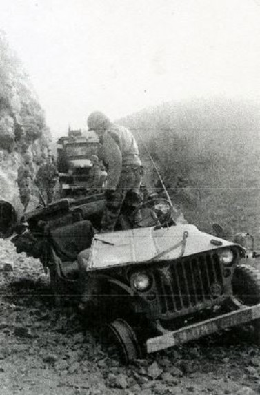 La roue avant droite a roulé sur un obus piégé .La carte  d' Etat Major est posée sur le capot le Capitaine Roger PHILIPPON - occupé à rendre compte par radio de cet incident -  était en tète du convoi régimentaire .Il a en effet eu beaucoup de chance ! Sur la calandre de la jeep un insigne du 9° RCP