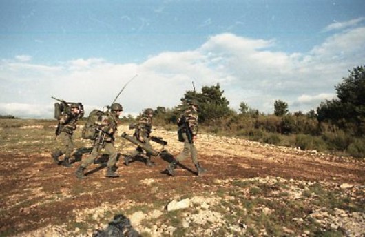   Progression en direction des emplacements de tir .Un Chef de Groupe avec une pièce Dispositions NBC non encore prises .Tous sont revêtus de la parka bariolée et coiffés du casque camouflé avec le même tissu que la parka .Sur un autre itinéraire ,une équipe chemine .. 