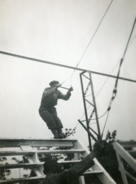   L' escalier , agrés à difficulté modulable . L'élève parachutiste se saisit d'un trapèze ( poignée  métallique ) fixé par un cordage à une poutre 