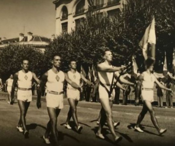 Tenue de parade blanche -espadrilles, short, maillot d’athlétisme - ceinture  élastique tricolore ( boucle fermoir en cuir ) des moniteurs.  Sur la poitrine dans un losange de tissu  il parait logique que ce soit l'insigne brodé de l’ENEPM .Mais la photo sur ce point est peu loquace.